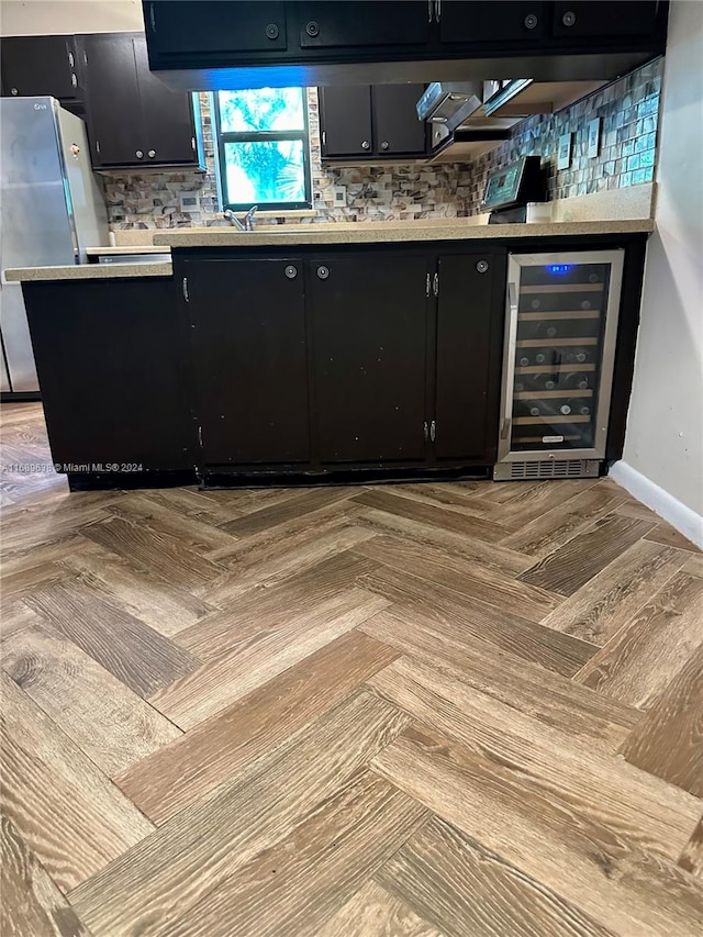 bar featuring backsplash, stainless steel refrigerator, and beverage cooler