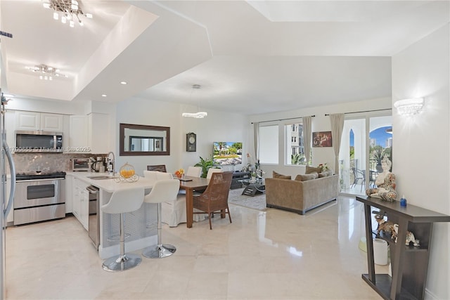 kitchen featuring sink, white cabinetry, stainless steel appliances, a kitchen bar, and kitchen peninsula