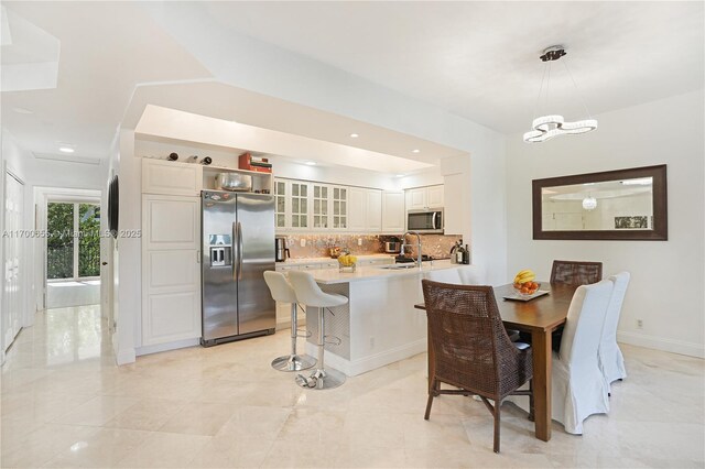 kitchen with sink, stainless steel appliances, backsplash, kitchen peninsula, and white cabinets