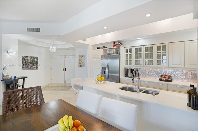 kitchen featuring stainless steel refrigerator with ice dispenser, tasteful backsplash, sink, pendant lighting, and white cabinetry