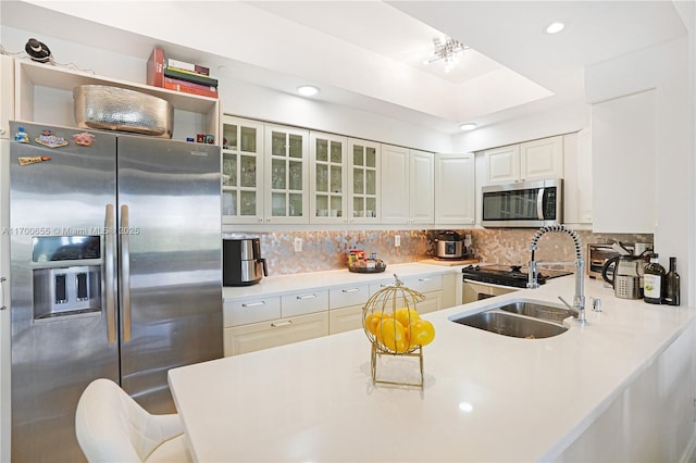 kitchen with sink, white cabinets, decorative backsplash, kitchen peninsula, and stainless steel appliances