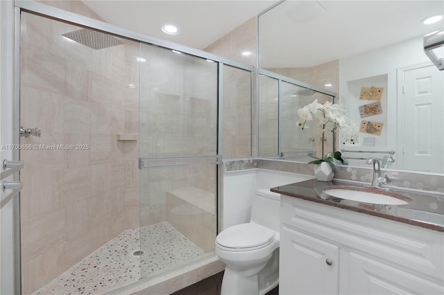 bathroom featuring vanity, walk in shower, and toilet