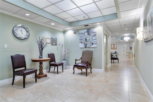 living area featuring light tile patterned floors and a paneled ceiling