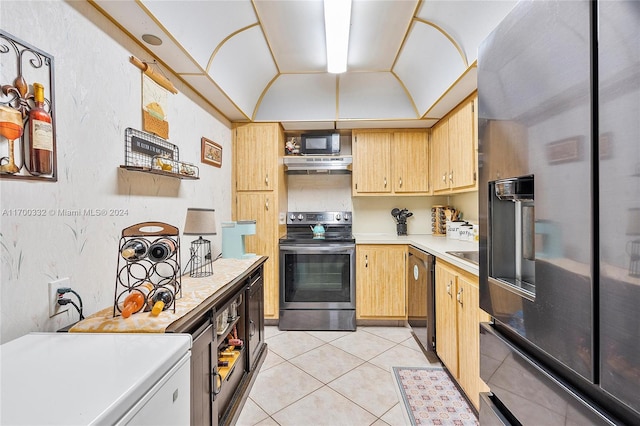 kitchen featuring black appliances, light tile patterned floors, and vaulted ceiling