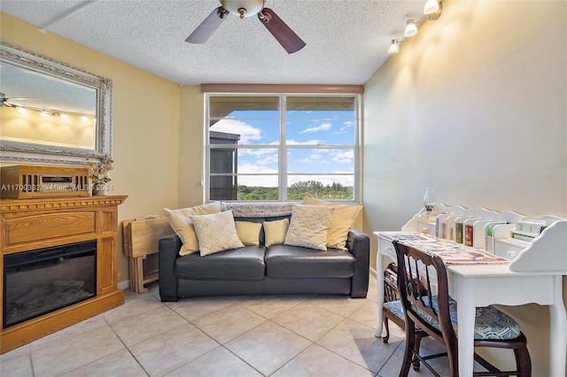 tiled living room with ceiling fan, rail lighting, and a textured ceiling