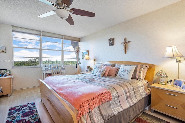 bedroom featuring hardwood / wood-style flooring, ceiling fan, a textured ceiling, and multiple windows