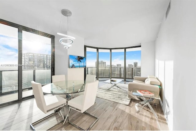 dining space featuring an inviting chandelier, expansive windows, and hardwood / wood-style flooring