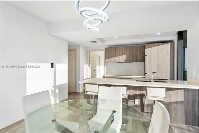 dining area featuring a notable chandelier, sink, and light hardwood / wood-style flooring