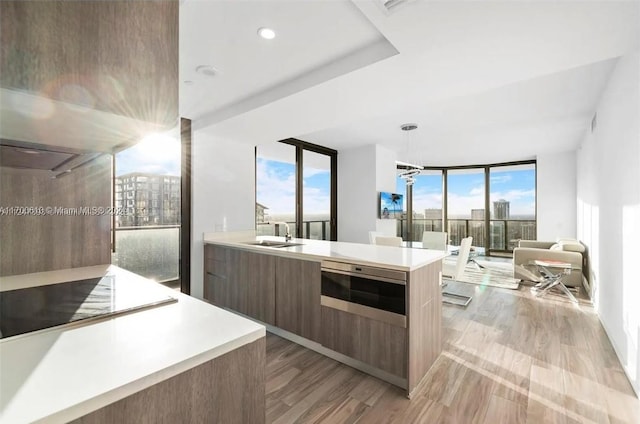 kitchen featuring stovetop, decorative light fixtures, light hardwood / wood-style flooring, and a wall of windows