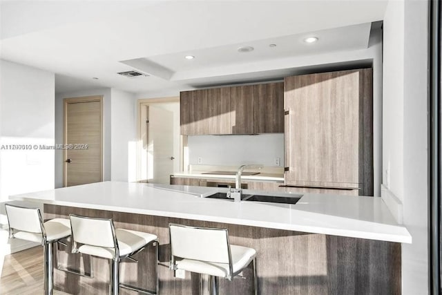 kitchen featuring a kitchen breakfast bar, light wood-type flooring, and sink