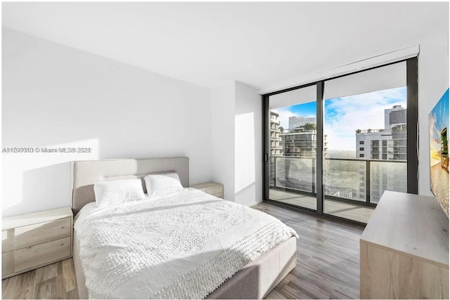 bedroom with access to outside, hardwood / wood-style floors, and expansive windows