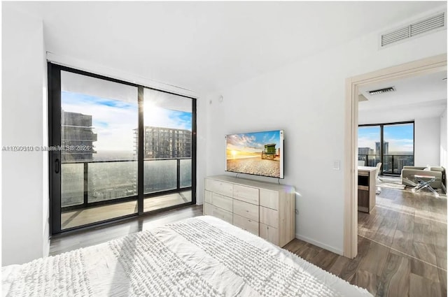 bedroom featuring hardwood / wood-style floors, access to outside, and a wall of windows