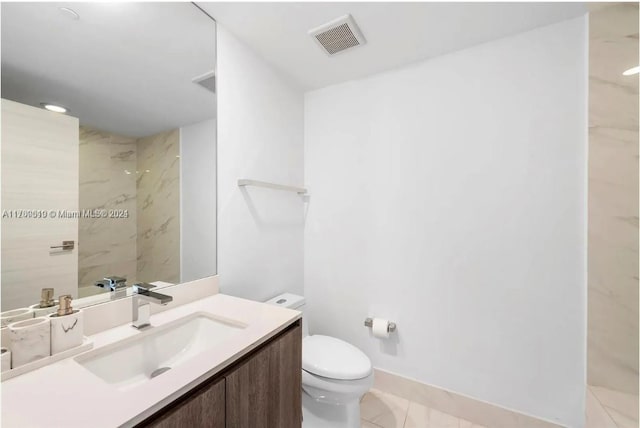 bathroom featuring tile patterned floors, vanity, a tile shower, and toilet