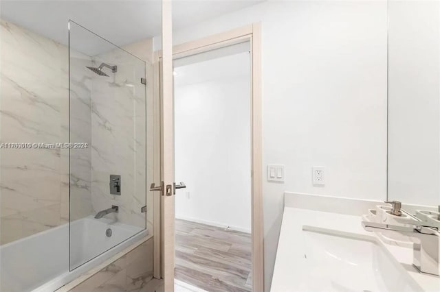 bathroom with hardwood / wood-style flooring, vanity, and tiled shower / bath