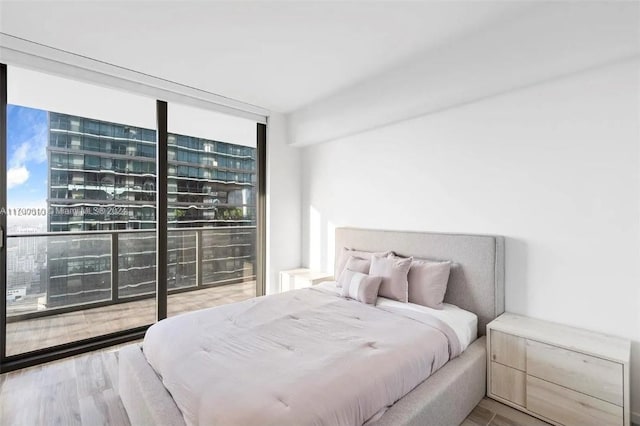 bedroom featuring multiple windows, expansive windows, and hardwood / wood-style flooring