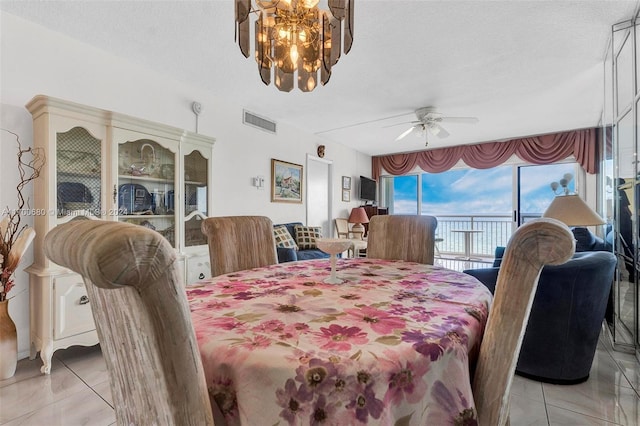 tiled dining area with ceiling fan with notable chandelier and a textured ceiling