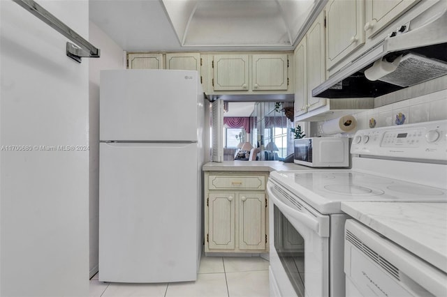 kitchen featuring cream cabinets, light tile patterned flooring, and white appliances