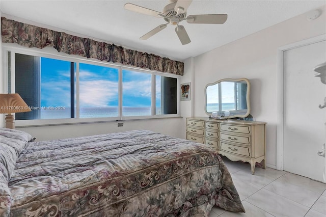 tiled bedroom with multiple windows, a water view, and ceiling fan