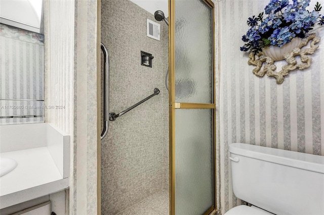 bathroom featuring vanity, toilet, and a shower with door