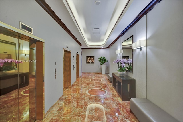 hall with a raised ceiling, crown molding, and elevator