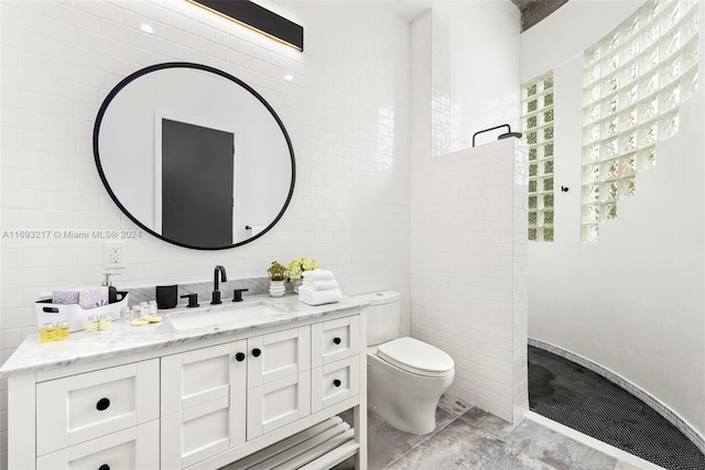 bathroom with vanity, toilet, and tile walls