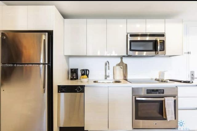 kitchen featuring appliances with stainless steel finishes, white cabinetry, and sink