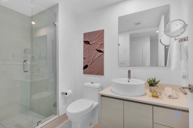 bathroom featuring vanity, toilet, and a shower with shower door