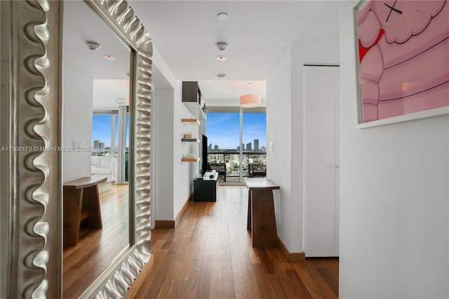 hallway with baseboards, a city view, and hardwood / wood-style floors