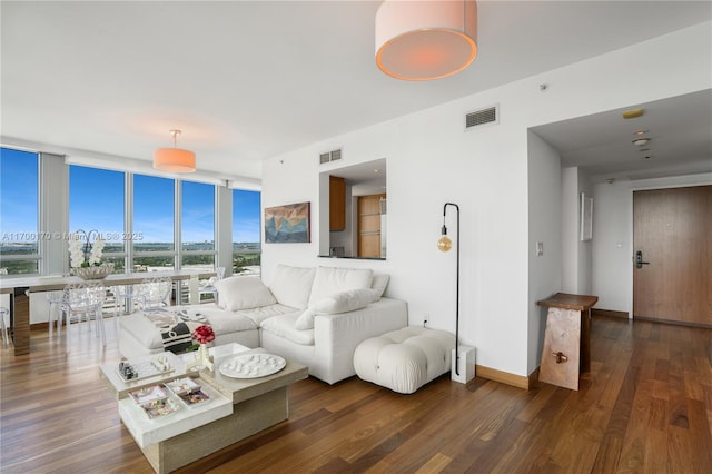 living area with floor to ceiling windows, visible vents, baseboards, and wood finished floors