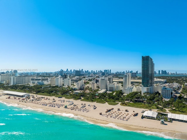 drone / aerial view featuring a water view, a beach view, and a city view