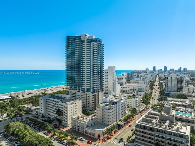 drone / aerial view with a water view, a view of the beach, and a city view