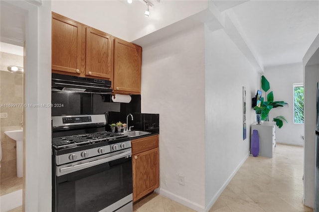 kitchen with backsplash, gas range, sink, and light tile patterned floors