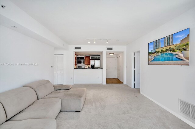 living room featuring rail lighting and light colored carpet