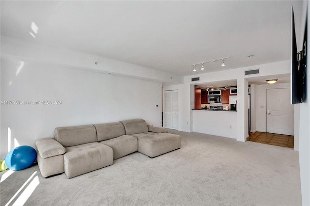 unfurnished living room with rail lighting and carpet floors