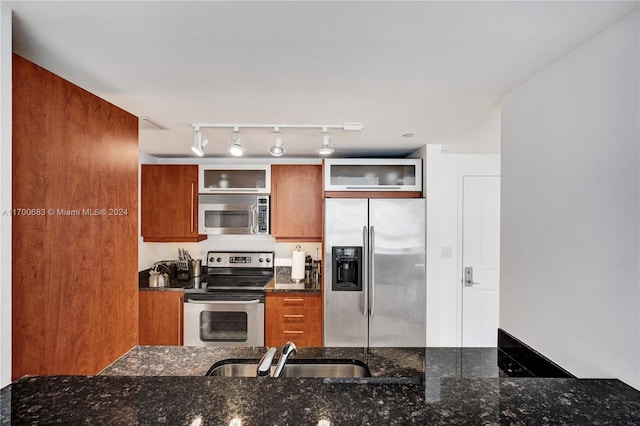 kitchen with sink, dark stone countertops, and stainless steel appliances