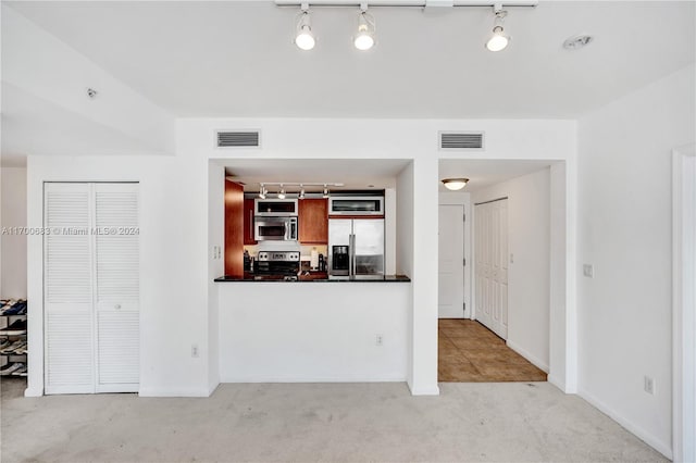 kitchen with appliances with stainless steel finishes, track lighting, and light carpet