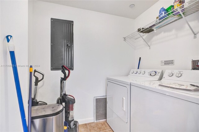 clothes washing area featuring electric panel, light tile patterned flooring, and independent washer and dryer