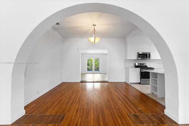 unfurnished living room with hardwood / wood-style flooring, crown molding, and french doors