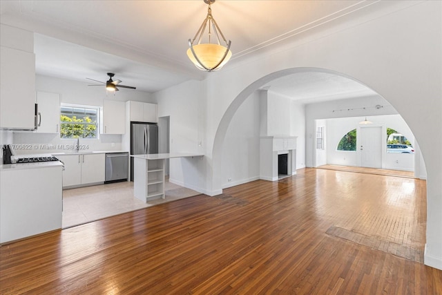 unfurnished living room featuring ceiling fan, sink, and light hardwood / wood-style flooring