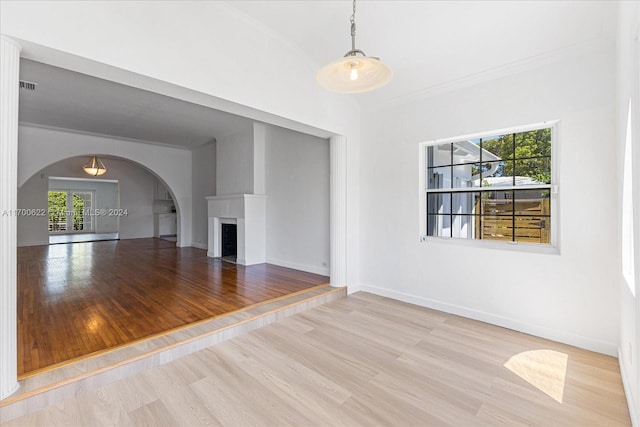 unfurnished living room featuring light hardwood / wood-style floors, crown molding, and a healthy amount of sunlight