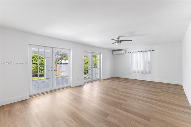 spare room featuring a wall unit AC, ceiling fan, french doors, and light wood-type flooring