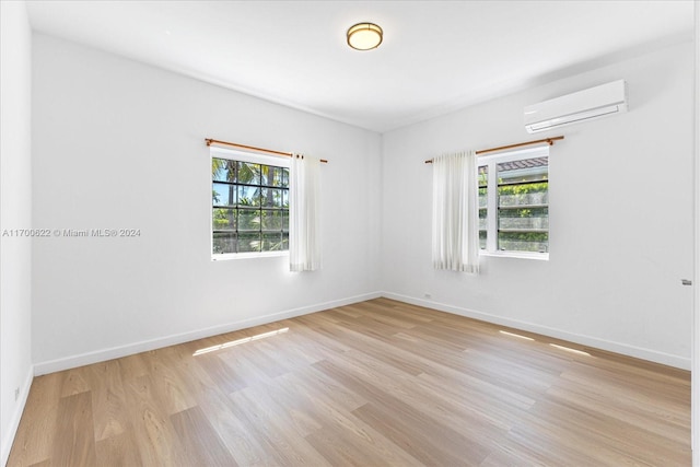 spare room with light hardwood / wood-style floors and an AC wall unit