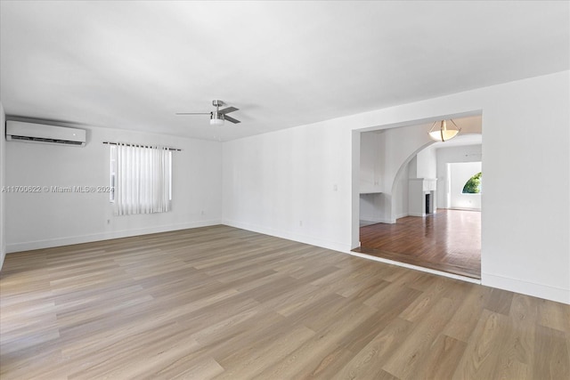 empty room featuring ceiling fan, light hardwood / wood-style floors, and a wall mounted AC