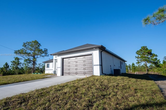 view of side of home with central AC, a garage, and a lawn