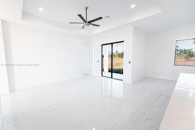 spare room with a raised ceiling and ceiling fan