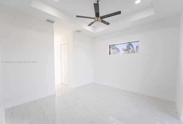 empty room featuring a raised ceiling and ceiling fan