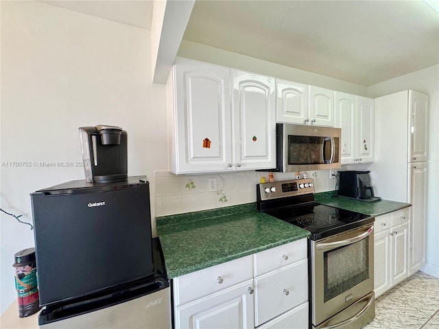 kitchen with tasteful backsplash, white cabinets, and appliances with stainless steel finishes