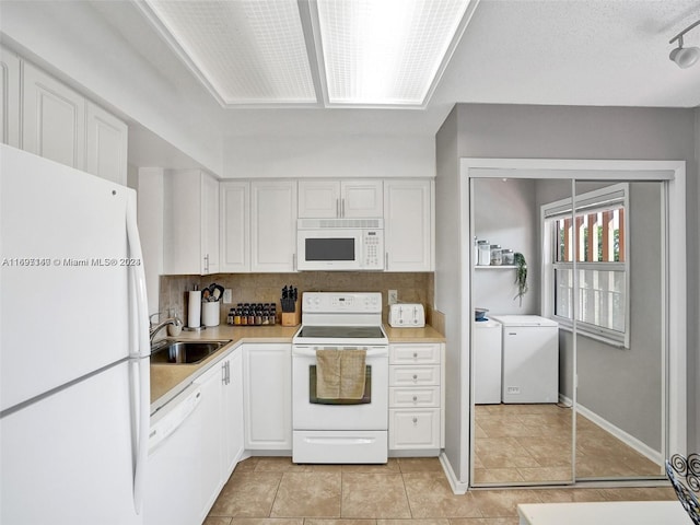 kitchen with washer and clothes dryer, white appliances, sink, decorative backsplash, and white cabinetry