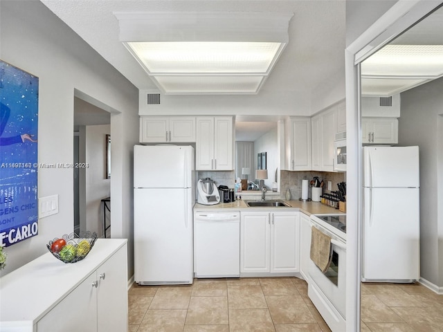 kitchen with white appliances, sink, light tile patterned floors, tasteful backsplash, and white cabinetry