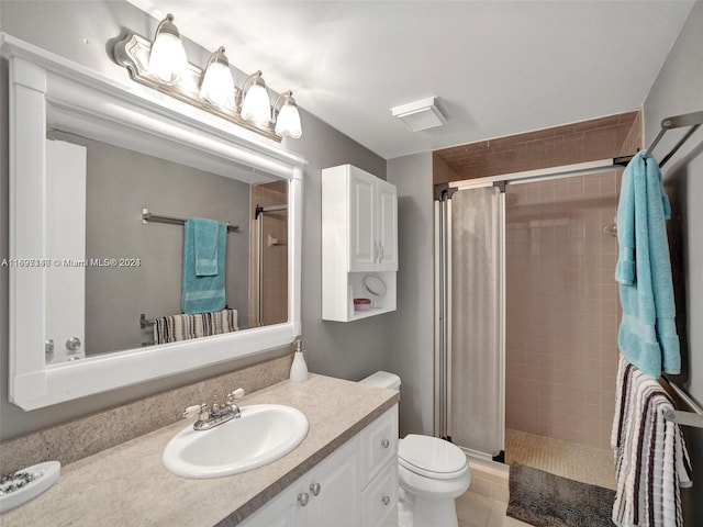 bathroom featuring tile patterned floors, vanity, toilet, and a tile shower